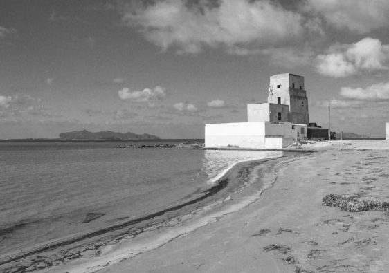 Black and white image of a historic beach tower in Trapani, Sicily with sweeping ocean views.