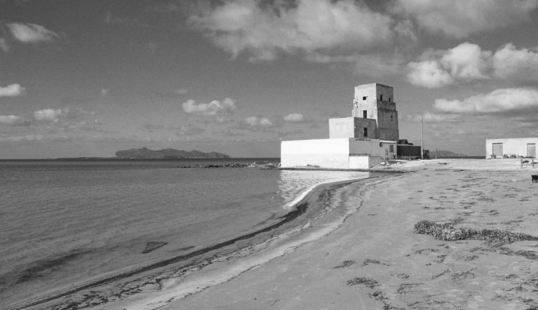 Black and white image of a historic beach tower in Trapani, Sicily with sweeping ocean views.